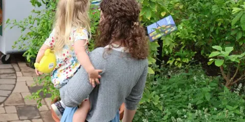 A woman holding a young child viewing plants inside the Buffalo and Erie County Botanical Gardens conservatory.