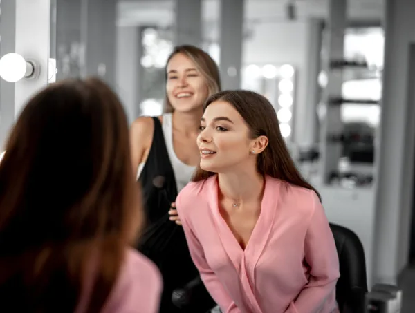 A professional beauty artist working on a client's hair and makeup in a studio setting.