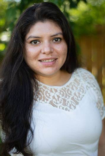 Portrait of Ciria Villalobos, a photographer with long dark hair wearing a white lace top.