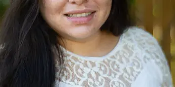 Portrait of Ciria Villalobos, a photographer with long dark hair wearing a white lace top.