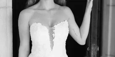 A bride in a white lace gown with styled hair and makeup standing in a doorway.