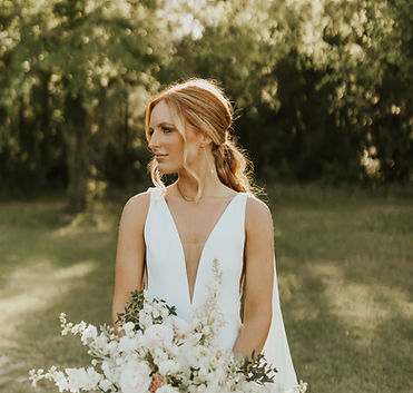 Bride in a white dress holding a white floral bouquet outdoors