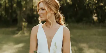 Bride in a white dress holding a white floral bouquet outdoors