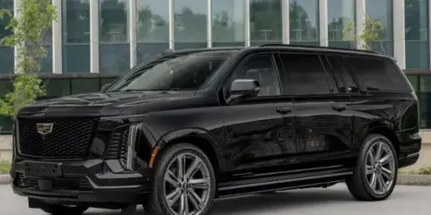 A black luxury SUV parked in front of a modern glass building.