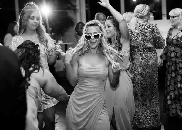 Black and white photo of a bride and guests dancing at a wedding reception.