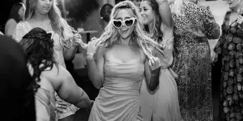 Black and white photo of a bride and guests dancing at a wedding reception.