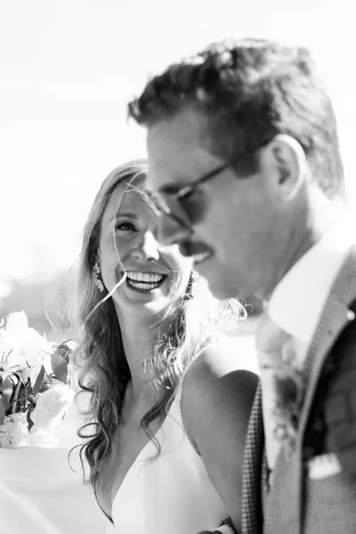 A black and white photograph of a smiling bride and groom at a wedding.