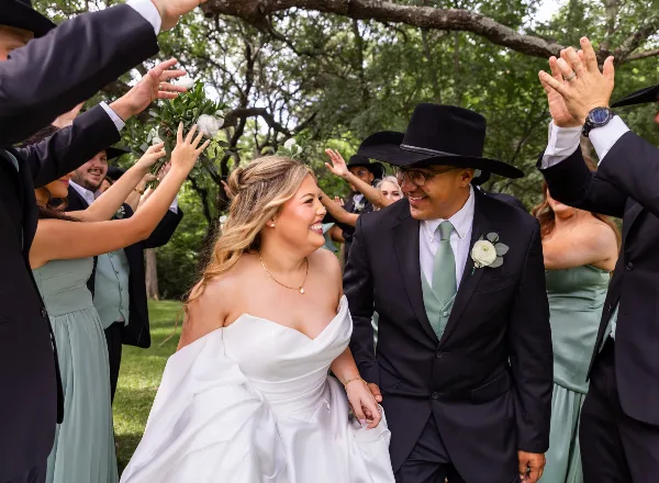 A bride and groom walking hand-in-hand through an outdoor venue surrounded by guests.