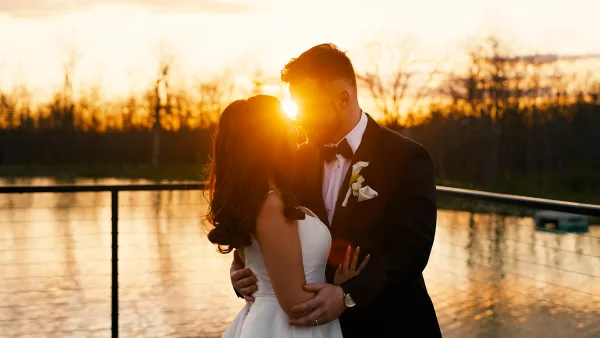 Bride and groom embracing at sunset by a lake, cinematic wedding film still