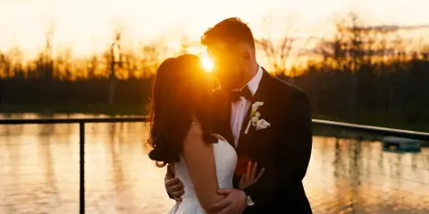 Bride and groom embracing at sunset by a lake, cinematic wedding film still