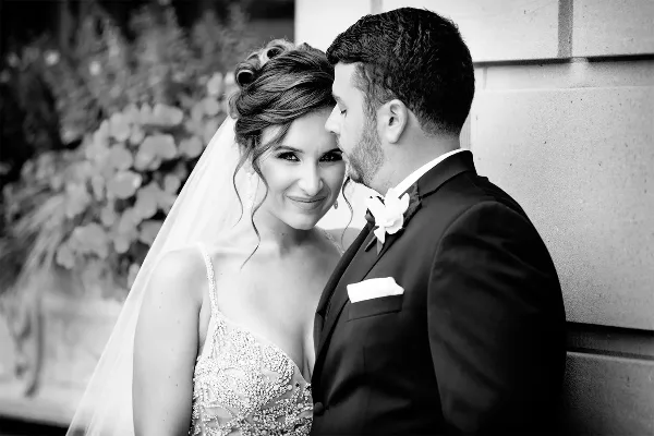 Black-and-white portrait of a bride and groom embracing during a wedding.
