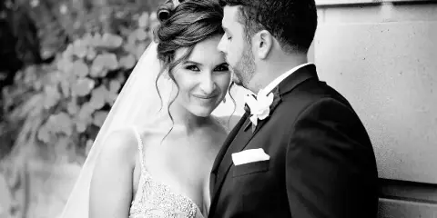 Black-and-white portrait of a bride and groom embracing during a wedding.
