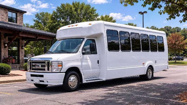 A white passenger minibus parked in a lot near a stone building.