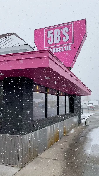Exterior of 5B's Barbecue restaurant with pink signage in snow