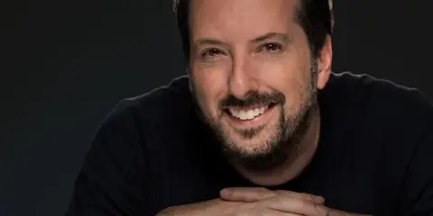 Professional portrait of a smiling man with a beard, wearing a dark shirt, with the Ryan Dinan Photography signature in the corner.