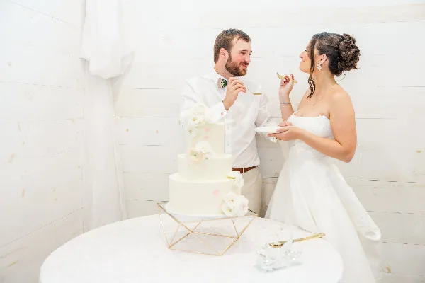 A bride and groom cutting a white three-tiered wedding cake with floral decorations.