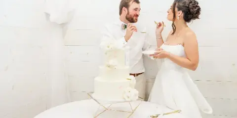 A bride and groom cutting a white three-tiered wedding cake with floral decorations.