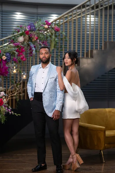 A bride and groom posing in a modern venue, showcasing the bride's styled hair and makeup.