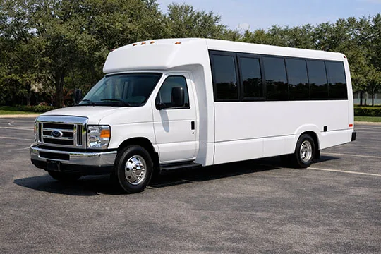 A white passenger shuttle bus parked in an outdoor lot.