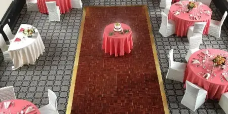 An overhead view of a wedding reception venue featuring round tables with pink tablecloths, white chairs, and a central cake table.