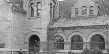 Historic stone building with a tower and arched windows, identified as the Carnegie Museum of Kings County.
