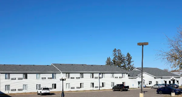 Exterior view of the Forty Club Inn motel building with a parking lot and clear blue sky.