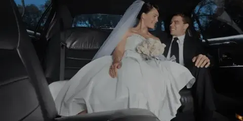 A bride and groom sitting in the back seat of a luxury car.