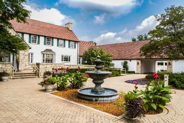 Exterior view of the Danada House historic mansion featuring a white facade, red roof, and a central stone fountain in a paved garden courtyard.