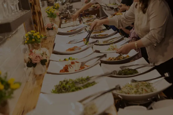 A buffet line with various food dishes and serving utensils at an event.