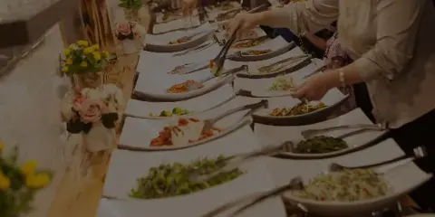 A buffet line with various food dishes and serving utensils at an event.
