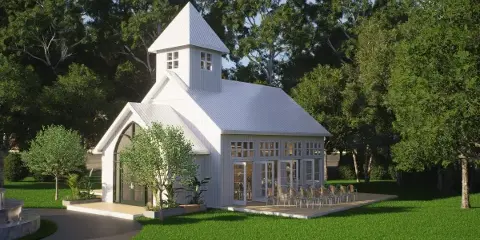 Architectural rendering of a white wedding chapel with a steeple and large windows, situated in a wooded area with a paved patio and chairs.