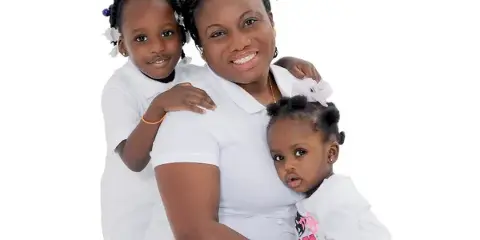 A professional studio portrait of a mother holding two young children against a white background.