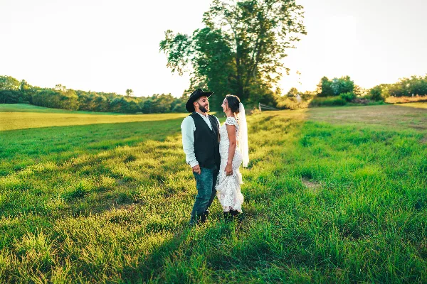 A bride and groom standing in a grassy field at a wedding venue.