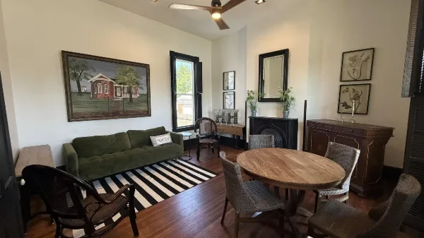 Interior view of The Hoffman House event venue showing a living area with a green sofa and a dining area with a round wooden table.