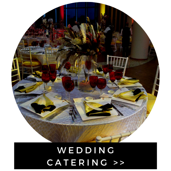 A formal event table setting featuring a floral centerpiece, red wine glasses, and yellow napkins.