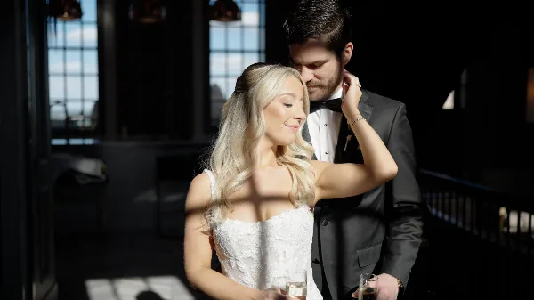 A cinematic wedding photograph of a bride and groom in a dimly lit, atmospheric interior setting.