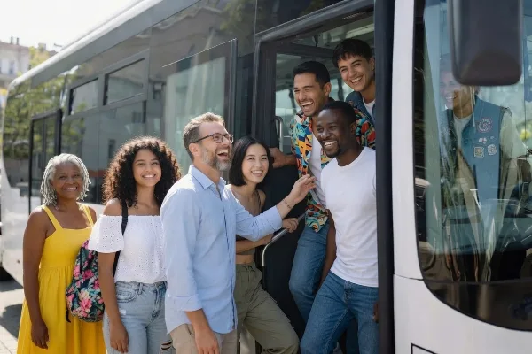 A group of smiling passengers boarding a white motorcoach bus.