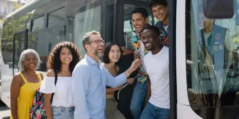 A group of smiling passengers boarding a white motorcoach bus.