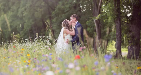 A bride and groom sharing a kiss in a field of wildflowers.