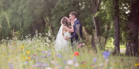 A bride and groom sharing a kiss in a field of wildflowers.