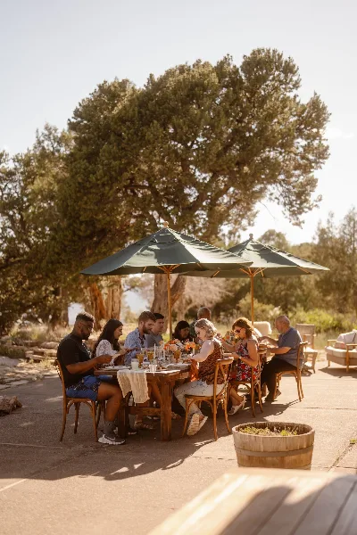Outdoor catering event with guests seated at a table under umbrellas