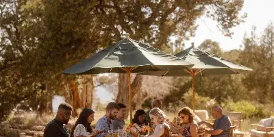 Outdoor catering event with guests seated at a table under umbrellas