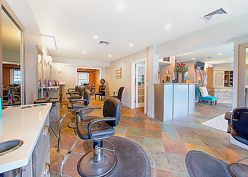 Interior view of a hair salon with styling chairs, mirrors, and a reception desk.