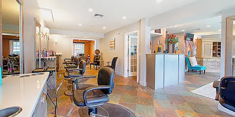 Interior view of a hair salon with styling chairs, mirrors, and a reception desk.