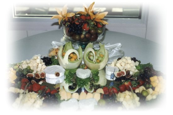 A catering display featuring a cheese and fruit platter with decorative garnishes.