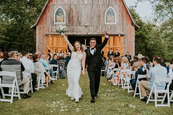 Bride and groom walking down the aisle at a barn wedding venue in Highfill, Arkansas
