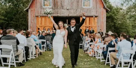 Bride and groom walking down the aisle at a barn wedding venue in Highfill, Arkansas