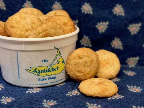 A white tub of The Nantucket Bake Shop macaroons with several cookies placed on a blue patterned cloth.