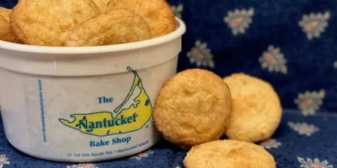 A white tub of The Nantucket Bake Shop macaroons with several cookies placed on a blue patterned cloth.