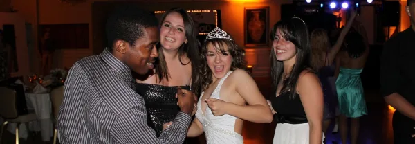 A group of young people, including a girl wearing a tiara, dancing and celebrating at a party.